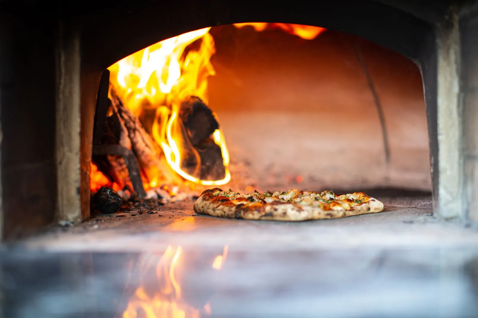 Pizzaiolo préparant une pizza au four à bois lors d'une réception en plein air